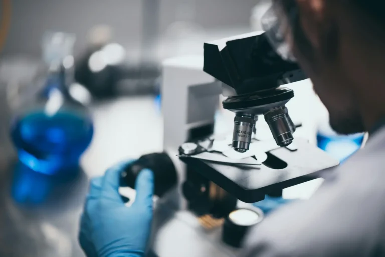Closeup of man looking into microscope in analytical testing lab
