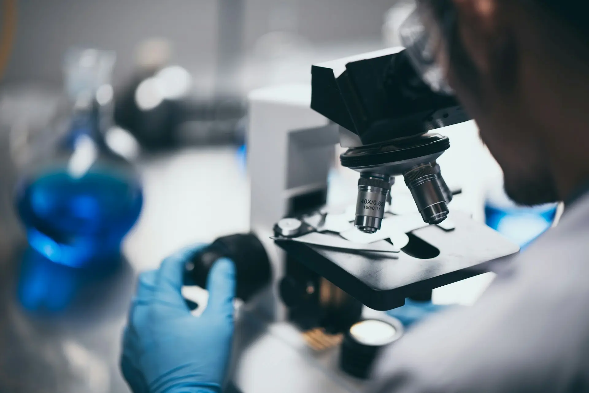 Closeup of man looking into microscope in analytical testing lab